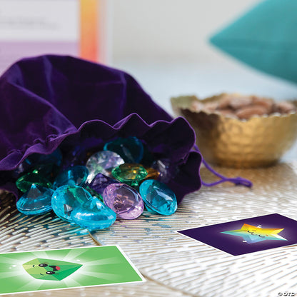 A purple velvet bag spills colorful plastic gems and two game cards on a patterned surface