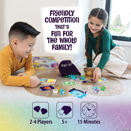 Smiling boy and girl play a gem-themed board game on the floor, surrounded by colorful plastic gems and cards