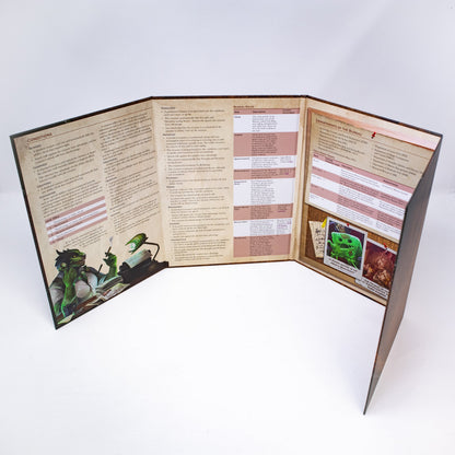 A Hit Point Press Big Bads Big Bad Bureau GM Screen stands open on a white surface, displaying game text, character art of a green creature, and monster images