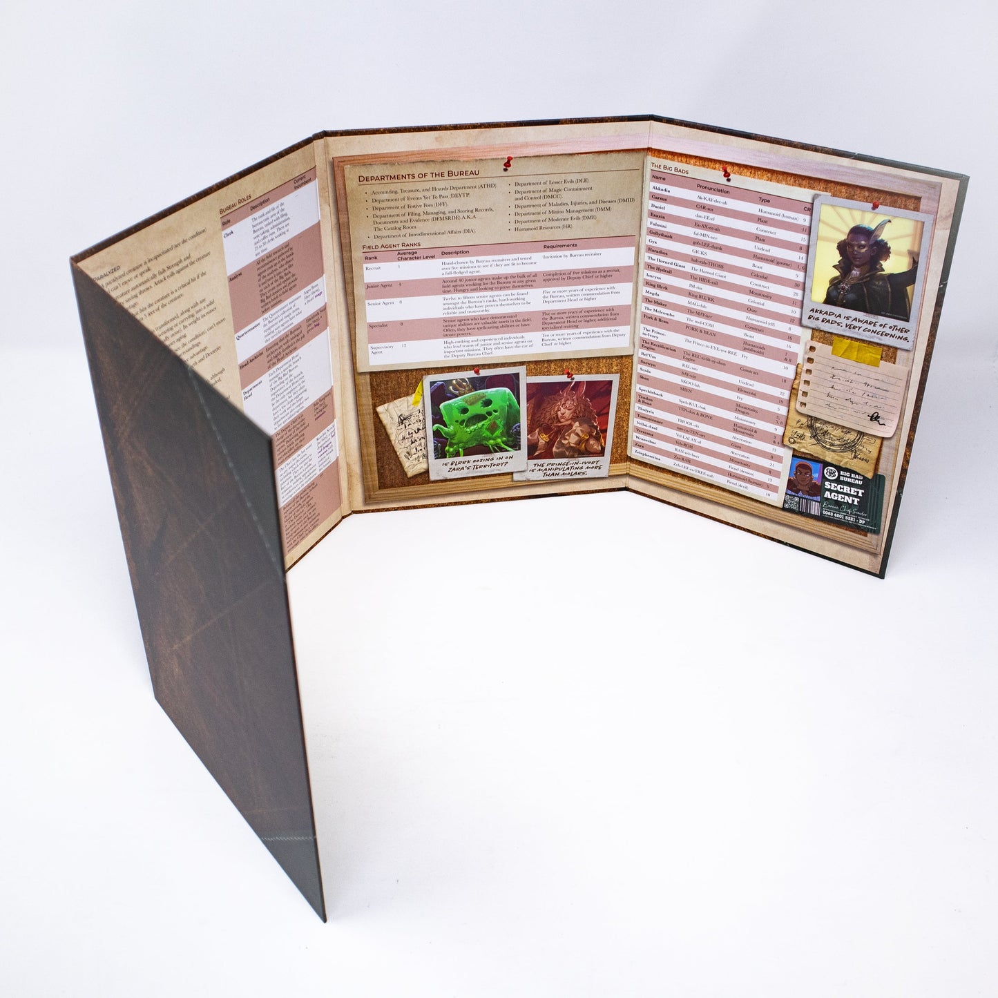 A four-panel Hit Point Press Big Bads Big Bad Bureau GM Screen is unfolded, displaying game information, character statistics, and fantasy creature images on a corkboard background