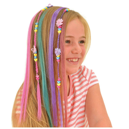 Smiling girl wearing colourful hair extensions (pink, teal, purple) decorated with beaded braids and flower charms