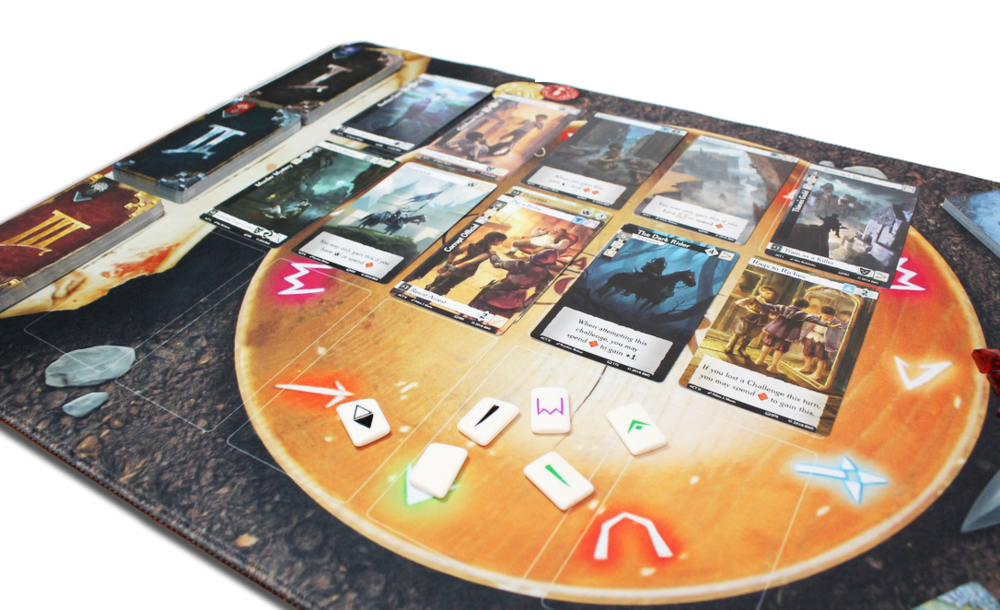 Close-up of a tabletop game in progress, showing numerous illustrated cards, decks, and white symbol tokens on a round playmat