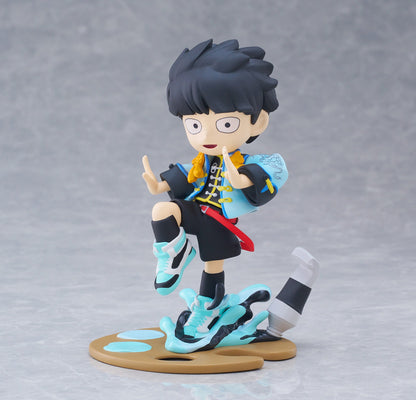 Figure in blue and black outfit with yellow scarf posing on a paint palette base with spilled blue paint and a paint tube on color background