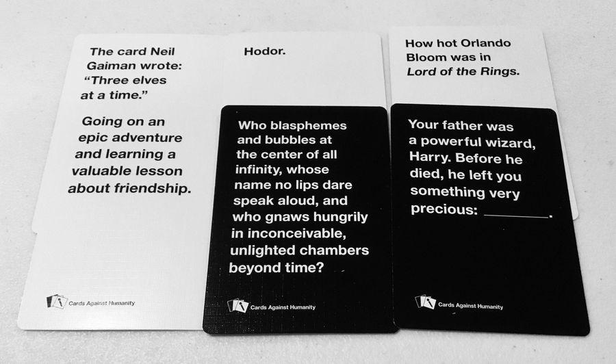 Three white and two black Cards Against Humanity cards displayed diagonally