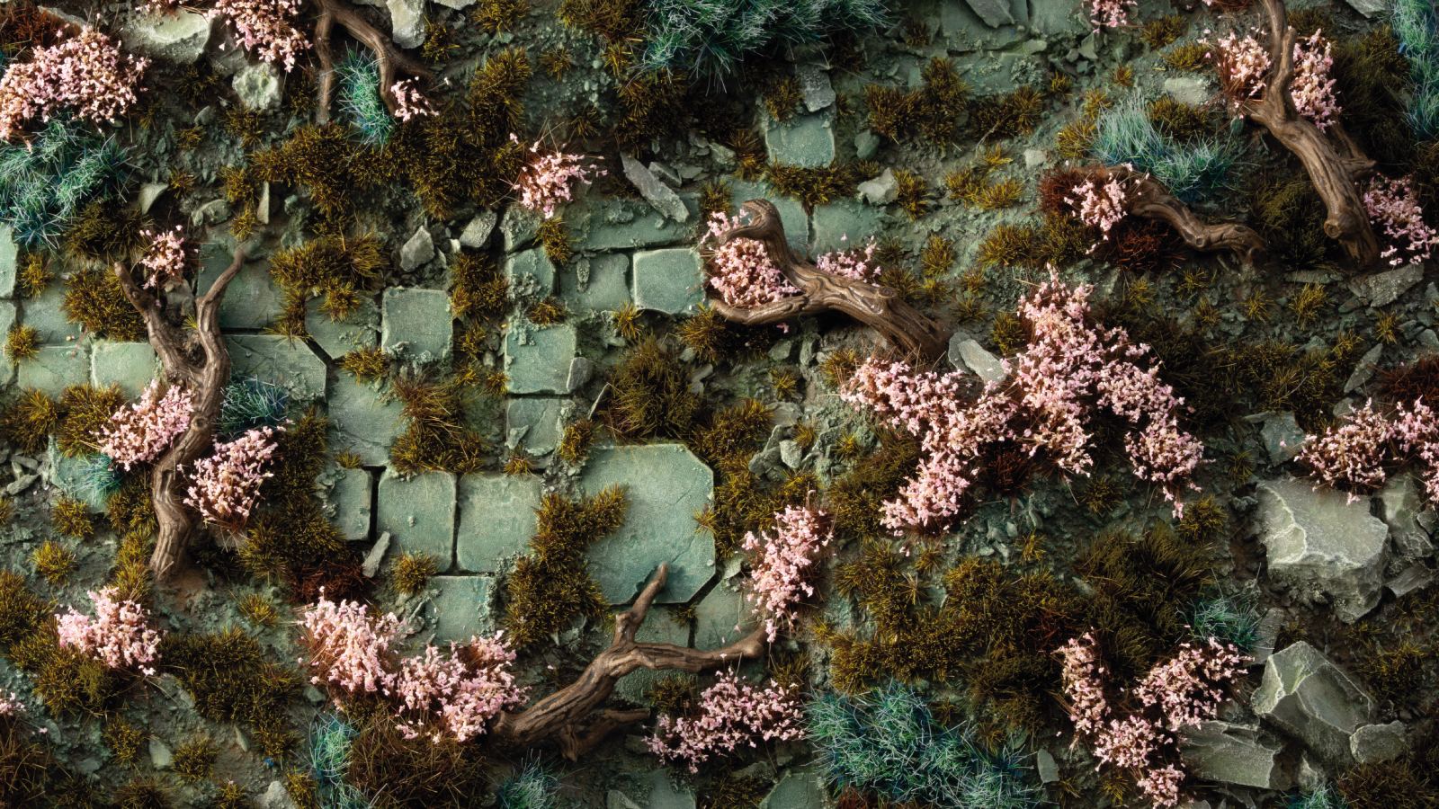 Miniature terrain: Pink flowers, twisted roots, and moss covering ancient green stone blocks