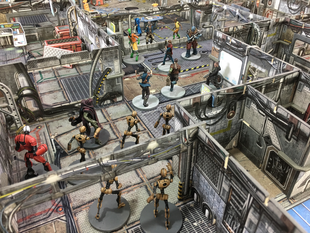 Sci-fi miniatures battling on a detailed modular board game map, featuring humanoids, robots, and a large monster