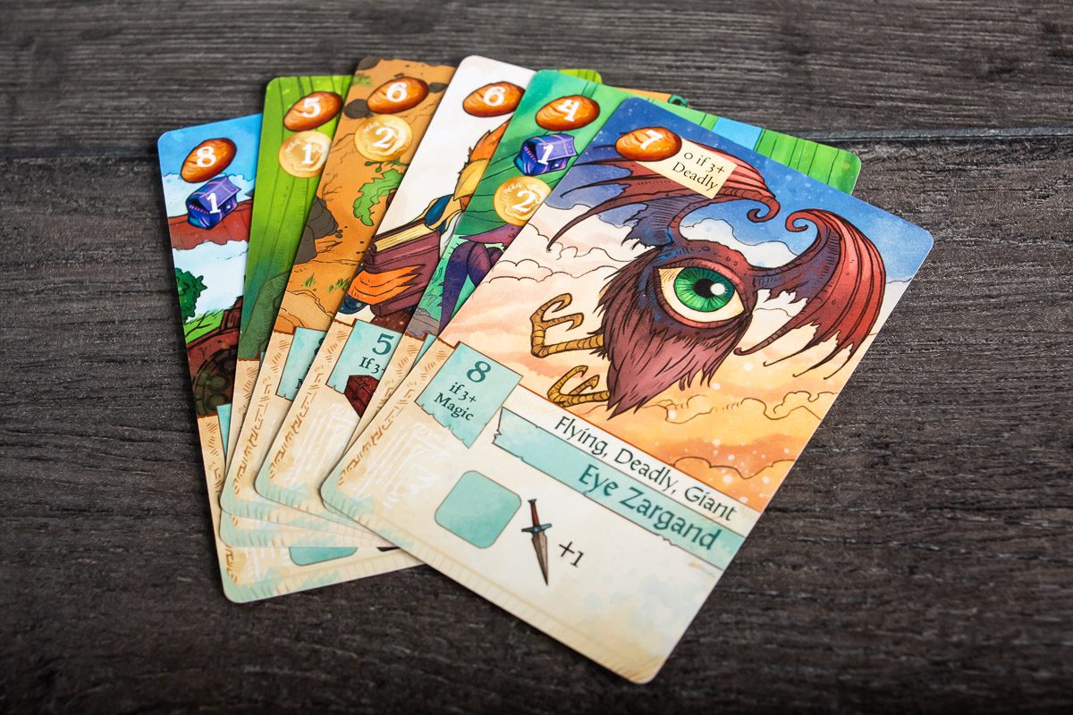 Colorful, fantasy-themed game cards on a dark wooden table and the front card