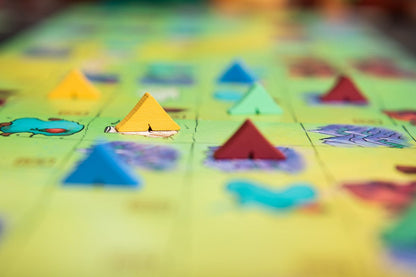 A close-up of a board game with colorful triangular wooden pieces on a light green map