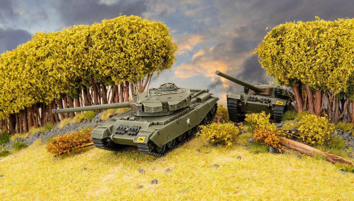 Two green model tanks on a grassy hill with vibrant yellow trees and a cloudy sky