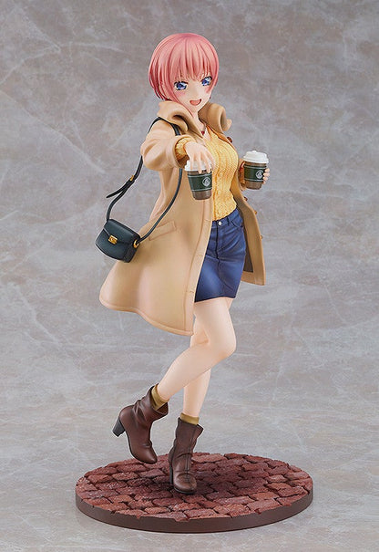 Anime figure of a pink-haired girl in a tan coat yellow sweater blue skirt and brown boots holding two coffee cups