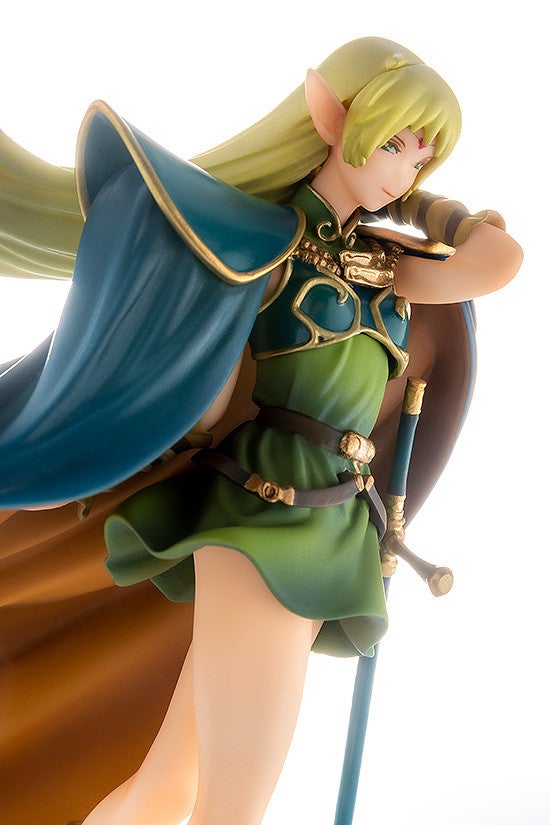 An elf figurine in a green and teal outfit with a cape and sword holding the sword across her chest