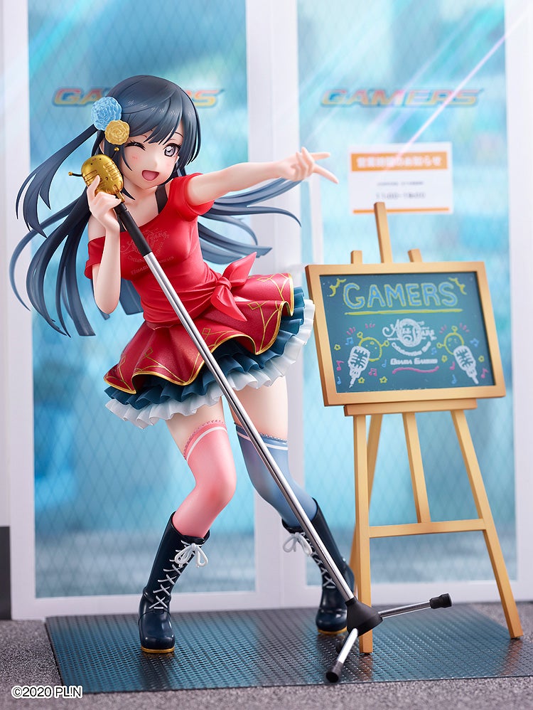 Vibrant anime figurine of a winking girl in a red idol outfit, holding a gold mic, posing by a Gamers store display.