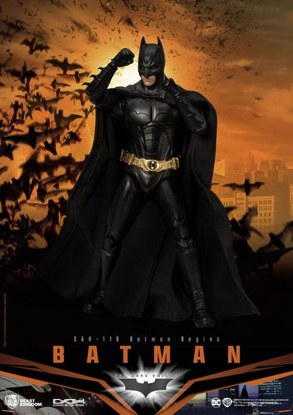 Batman action figure in black suit with golden belt and cape standing in fighting pose against orange sky and city skyline with bats flying