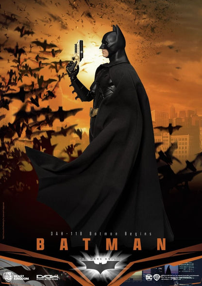 Batman Begins collectible figure holding a gold gun with a flock of bats in the background at sunset