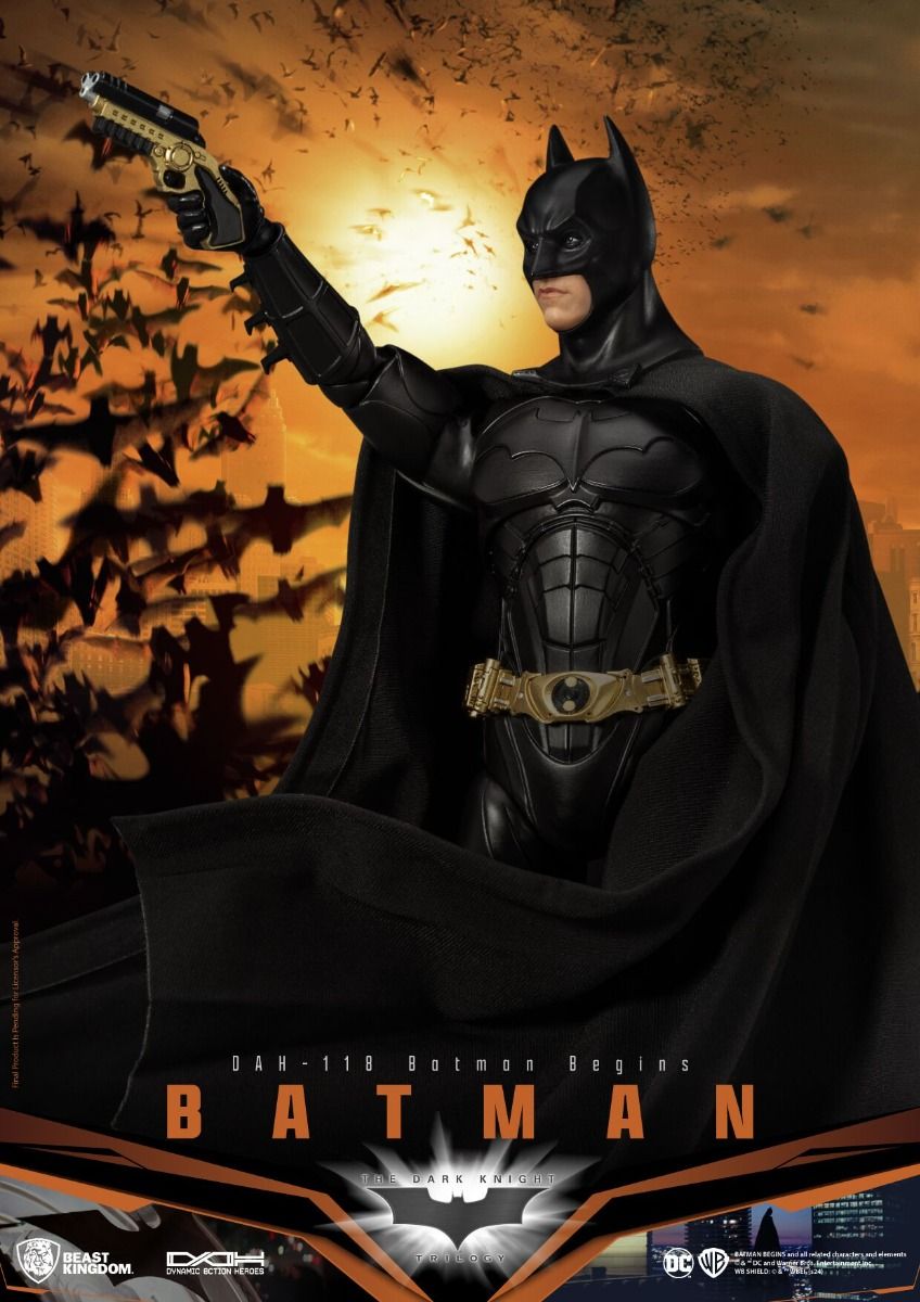 Highly detailed Batman action figure from Batman Begins in black suit with gold belt holding a grapple gun set against a sunset city backdrop with bats flying
