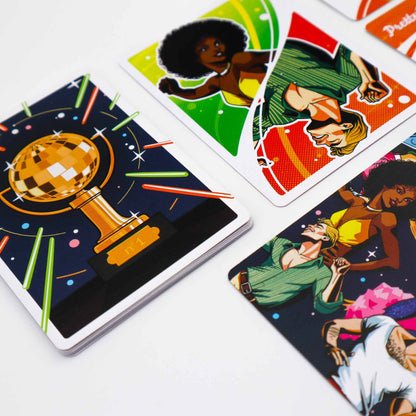 Colorful game cards: a disco ball trophy card on top of a stack, with other cards showing dancing figures