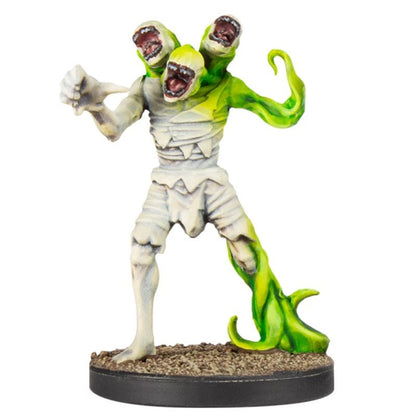 Horrific miniature: a bandaged creature with three open-mouthed heads and green, vine-like limbs, lunging forward