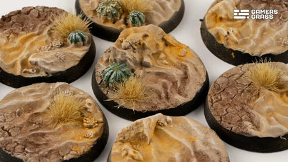 Textured miniature bases simulating desert terrain, featuring sand, rocks, dry tufts, and cacti