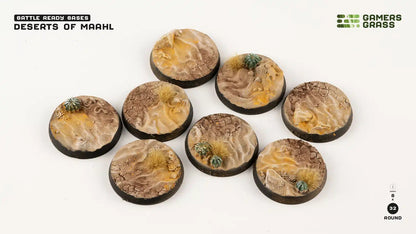 Eight round, pre-finished miniature bases showing arid desert terrain with textured sand, cracked earth, and cacti