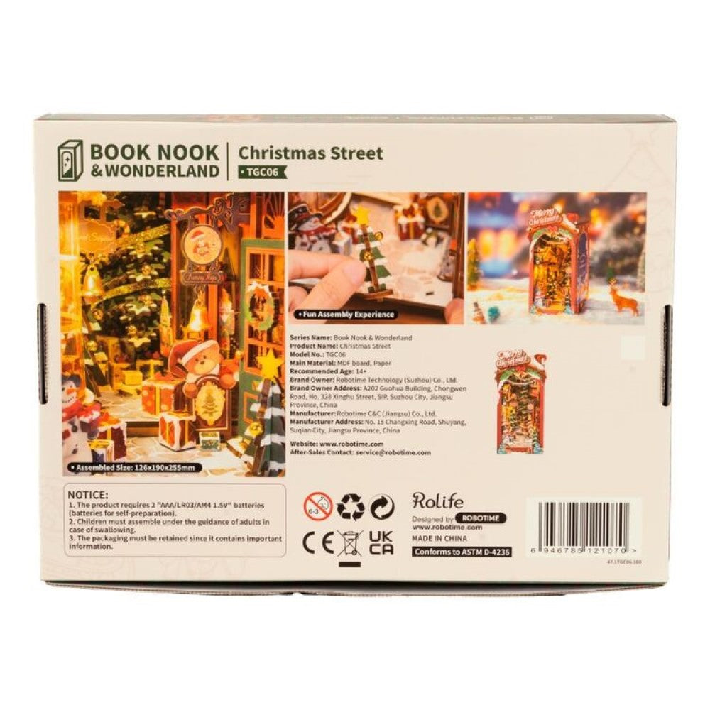 Box for the "Christmas Street" Book Nook DIY kit, showing the assembled, lighted miniature holiday scene with a teddy bear