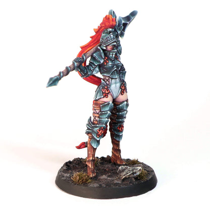 Painted miniature of a female warrior in dark armor with bright red hair, wielding a polearm on a dirt base