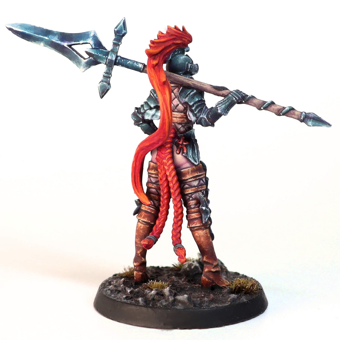 Miniature warrior in dark armor with long red braids, viewed from behind, carrying an ornate polearm