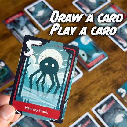 A hand holds a game card depicting a furry, multi-legged monster, Other cards are on a wooden table with text: DRAW A CARD PLAY A CARD