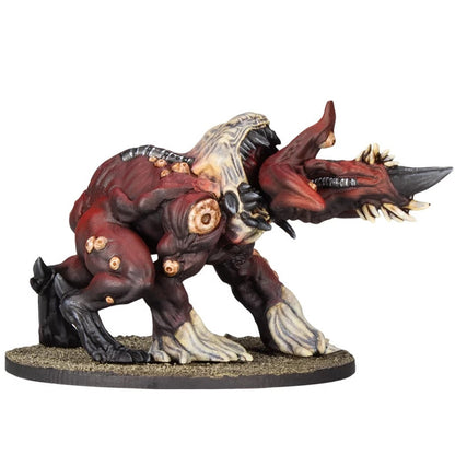 Grotesque red monster miniature with multiple fangs, a horn, and visible mutations, posed aggressively on a base