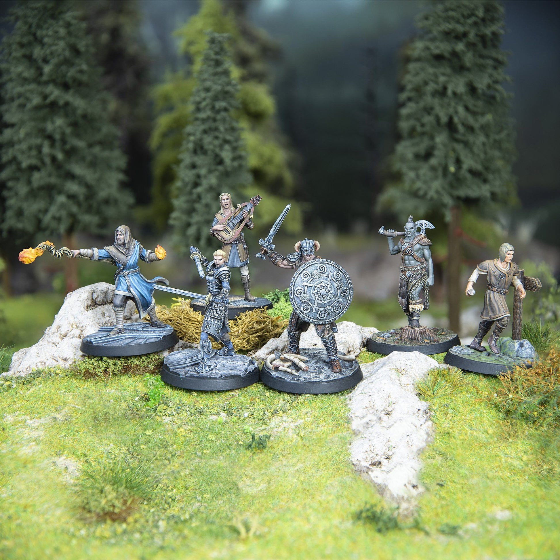 Six detailed fantasy miniatures: a warrior with shield, a mage casting fire, an orc, a bard, and two others, on a forest diorama