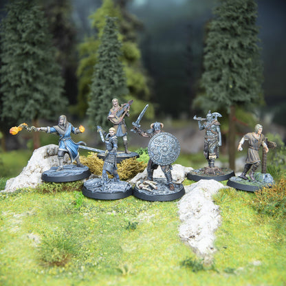 Six detailed fantasy miniatures: a warrior with shield, a mage casting fire, an orc, a bard, and two others, on a forest diorama