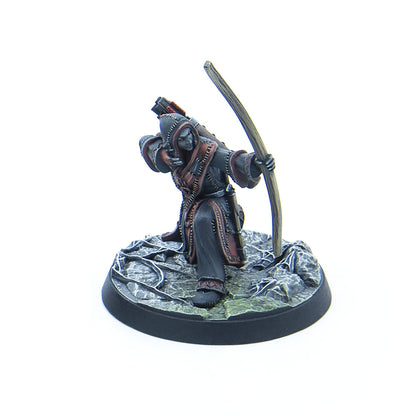 A hooded miniature figure with dark skin and red eyes, drawing a bow, standing on a rocky base