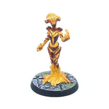 A painted miniature of a yellow and orange swirling fire elemental on a textured grey base