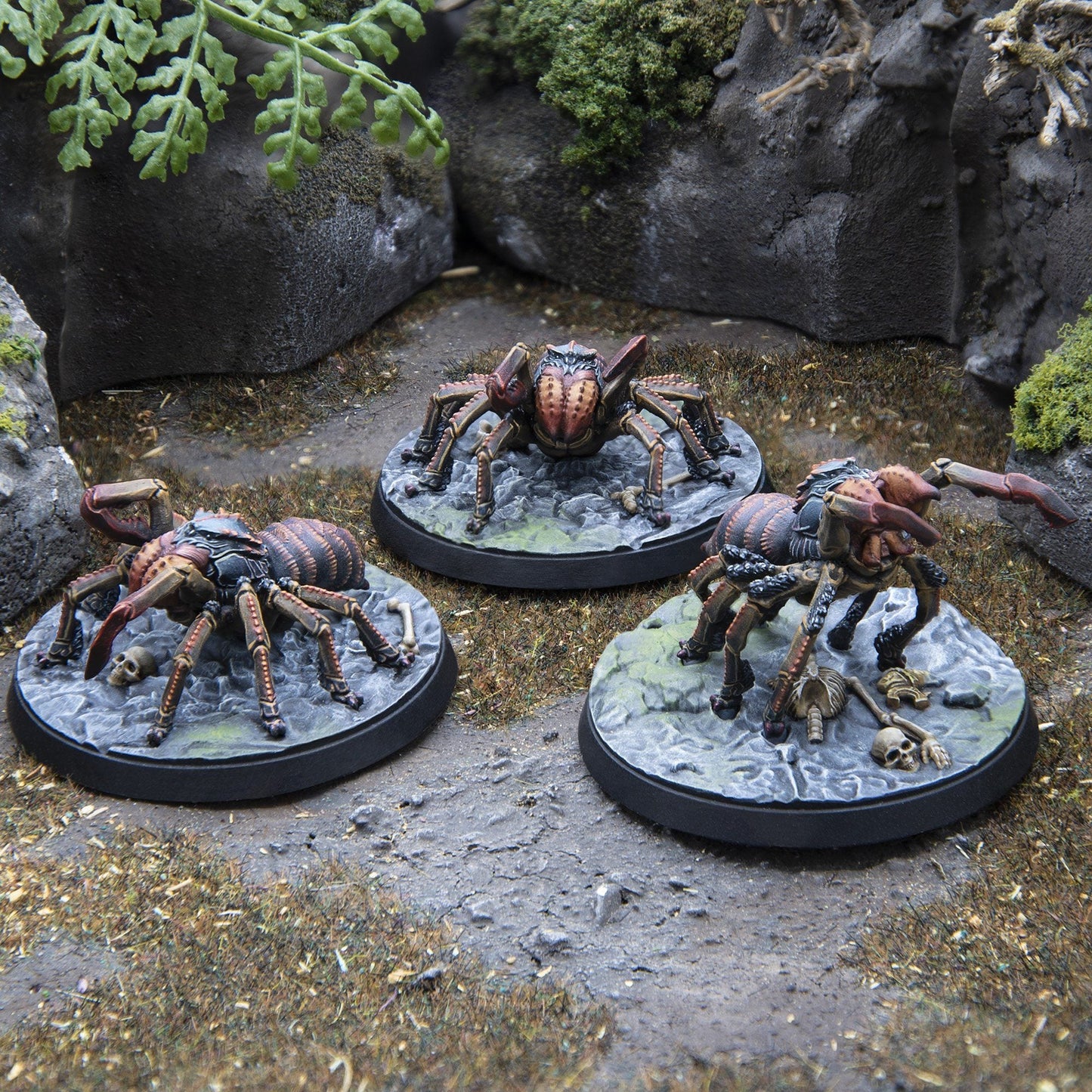 Three painted spider wargame miniatures features dark brown bodies, multiple legs, and claws 