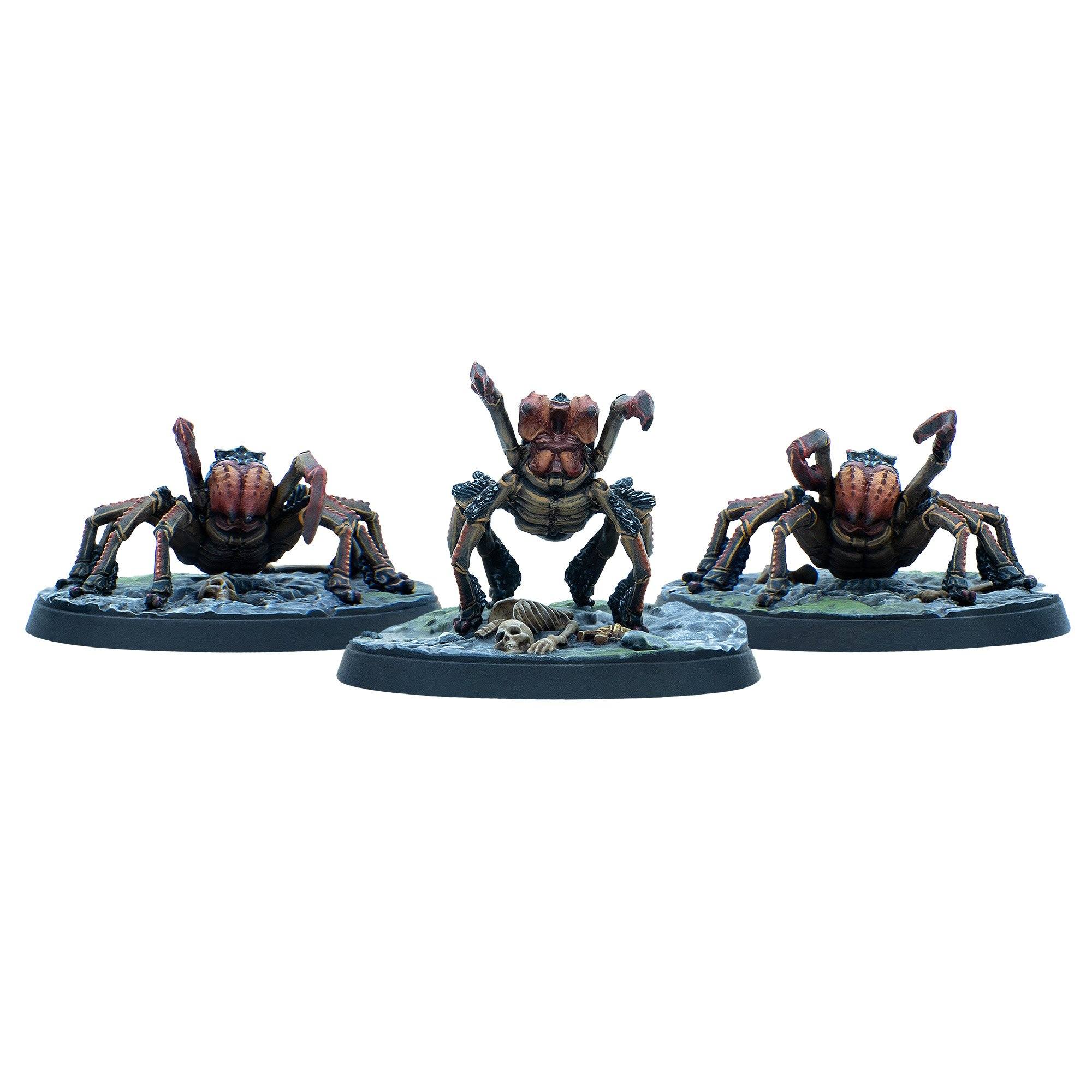 Three brown and red spider-like miniatures on bases, the central one rears up over a small skeleton