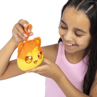 Smiling girl holding an orange and yellow plush cat keychain