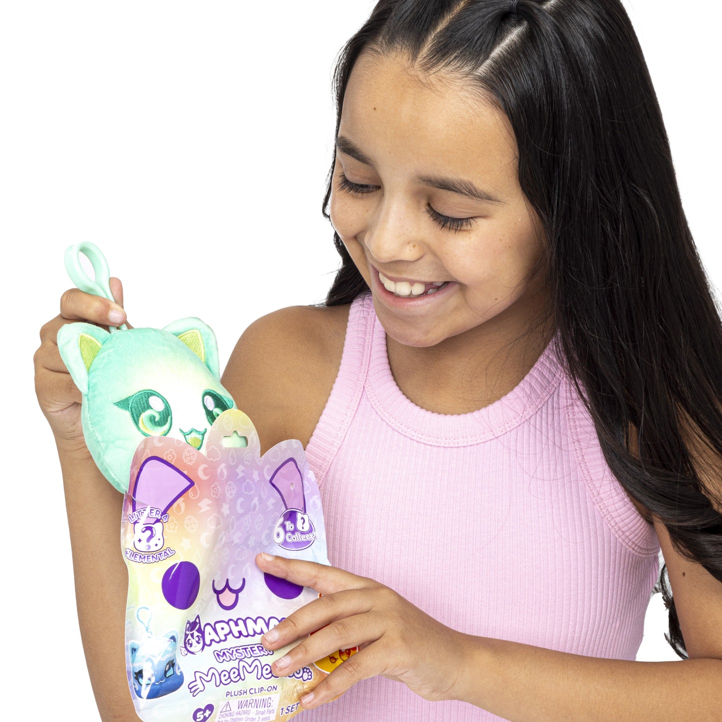 Happy girl holding a green Aphmau MeeMeows plush clip-on toy and mystery packaging