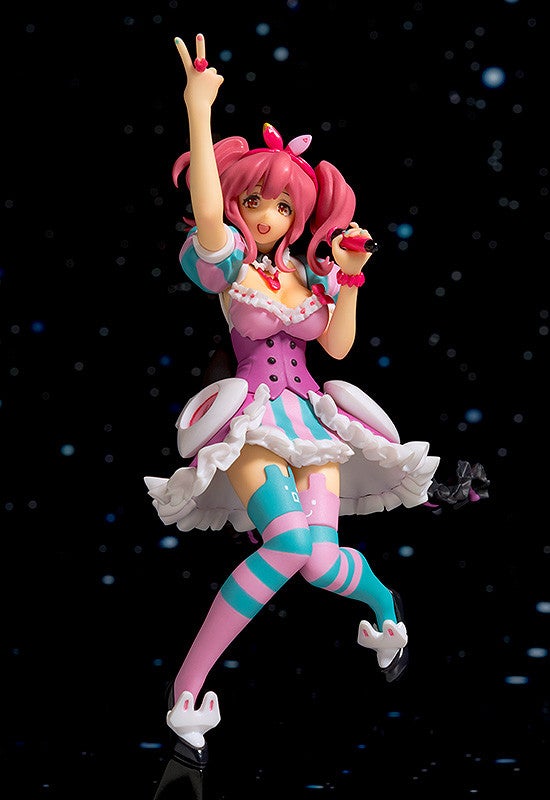 Bright pink anime figure in stage costume with striped socks holding a microphone and making a peace sign