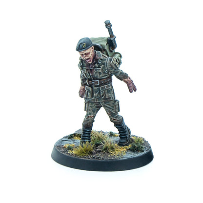 Miniature of a zombie soldier wearing a green beret and tattered camo, with an open mouth, shambling forward on a terrain base