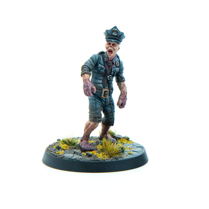 Miniature zombie police officer in tattered blue uniform and cap, mouth open, lurching forward on a scenic base