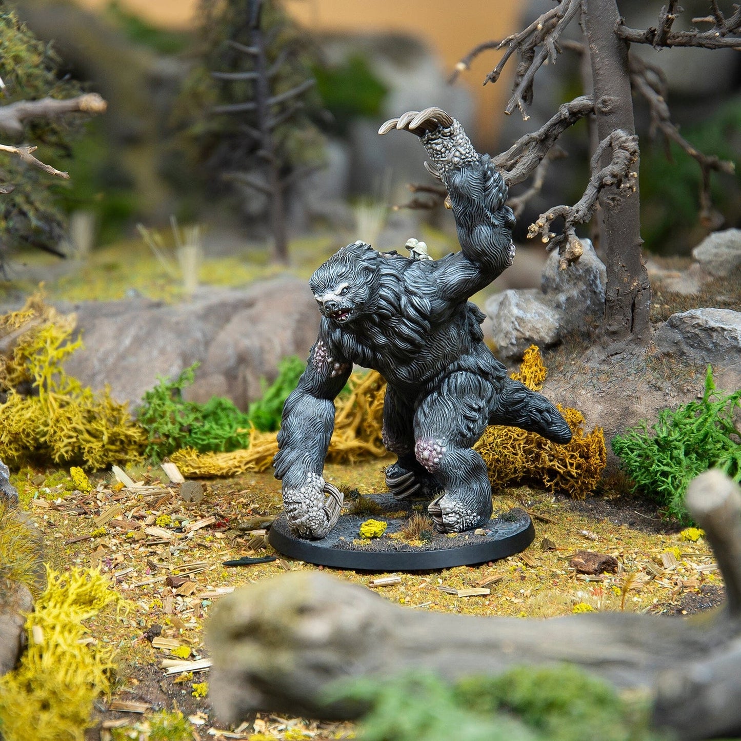 Hand-painted miniature of a dark, hulking beast with raised claw, displayed on a detailed forest diorama base