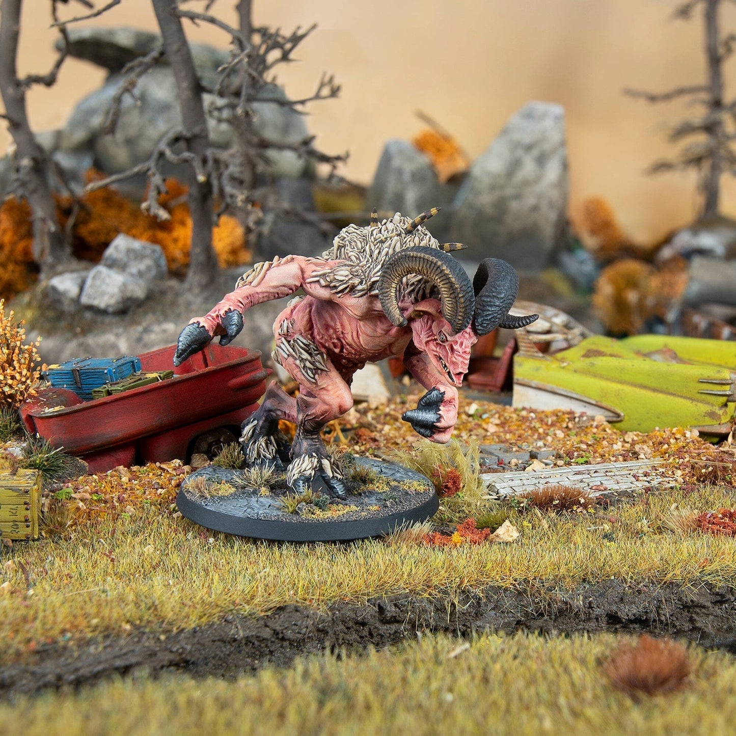 Miniature of a pink, ram-horned mutant charging in a detailed wasteland diorama with wreckage