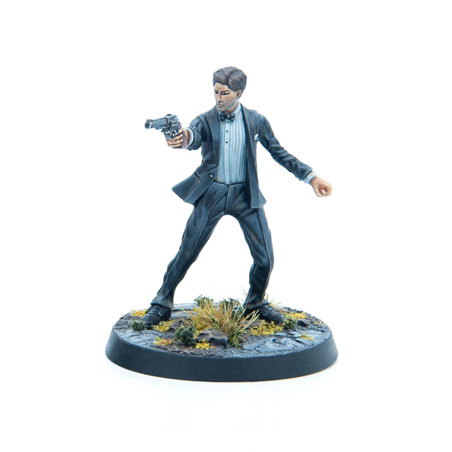 A painted miniature figure of a man in a dark suit and bow tie, aiming a pistol forward.