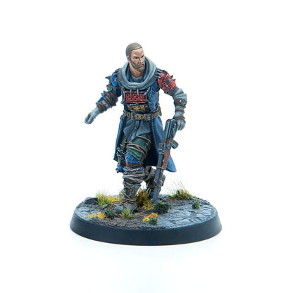 A painted miniature of a bearded man in rugged blue clothing, holding a rifle and advancing on a textured base.