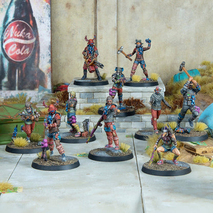 Ten painted Fallout miniatures depicting diverse wasteland raiders, armed with various weapons, posed on a diorama with a Nuka-Cola sign