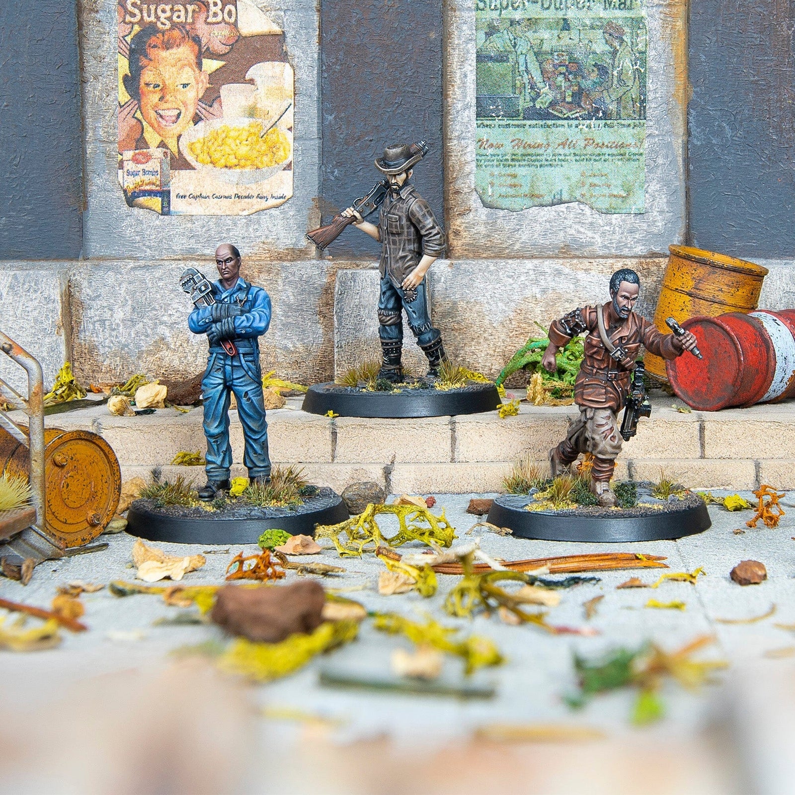 Three painted Fallout miniatures: a man with a wrench, a rifleman, and a running man with a pistol, in a ruined setting.