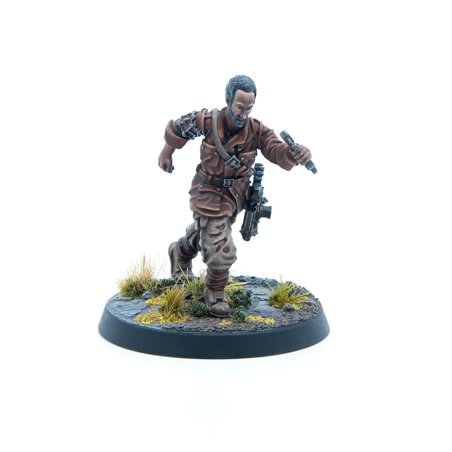 Painted miniature of a dark-skinned man with a beard, running in a brown uniform, holding a detonator and rifle on a terrain base.