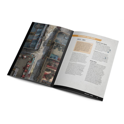 Game book open to an isometric map of ruined, abandoned shop fronts and streets in a post-apocalyptic setting