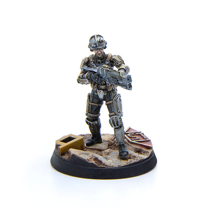 A detailed miniature figurine of a sci-fi soldier in full armor with a large rifle stands on a rocky base