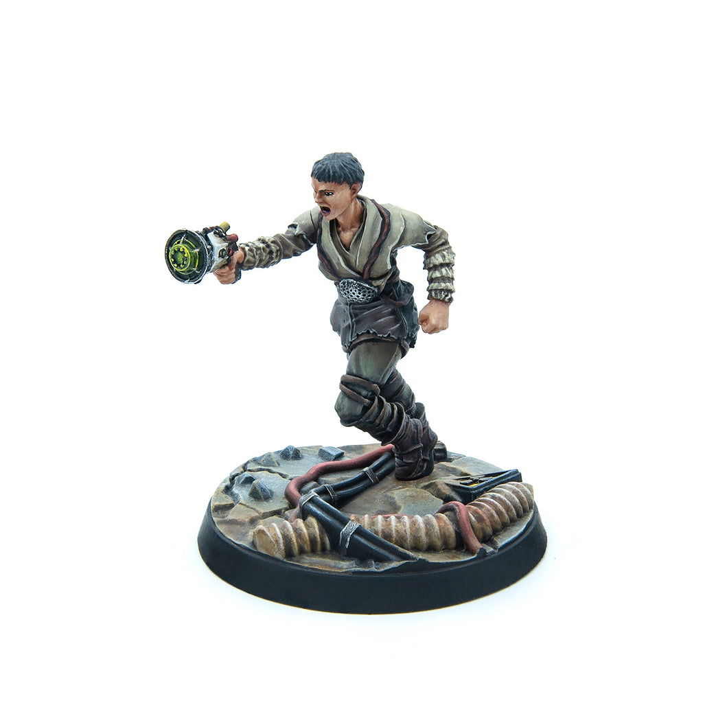 Painted miniature of a woman running in worn clothes, aiming a glowing green energy weapon on a debris base