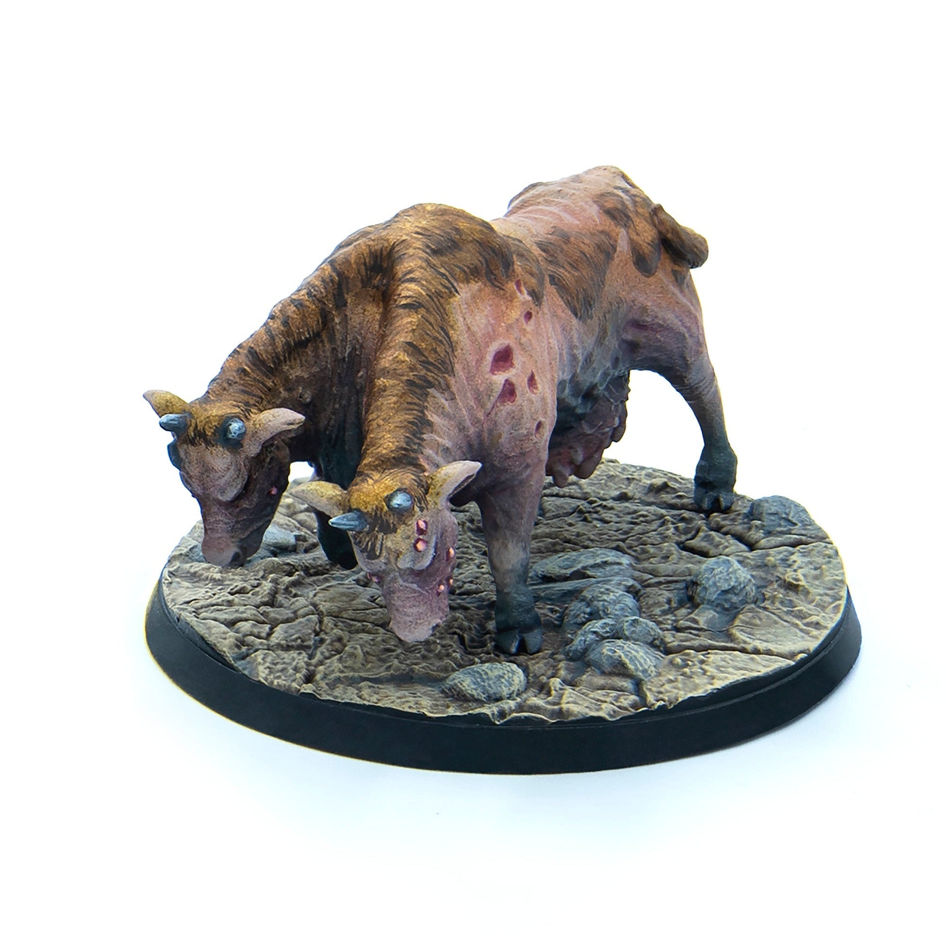 A miniature of a two-headed mutated cow with blue eyes and reddish lesions stands on a rocky base